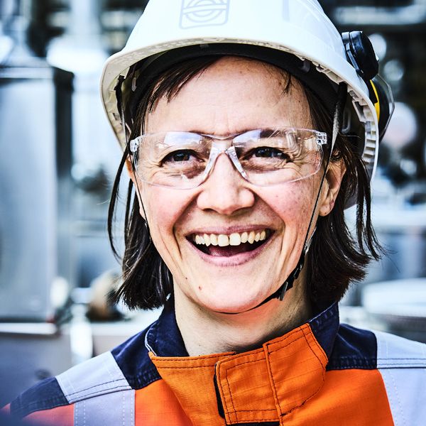 Portrait einer lächelnden Frau mit Schutzbrille und Helm