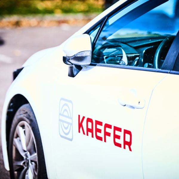 Seitenansicht auf ein weißes Auto mit KAEFER Logo auf der Seite