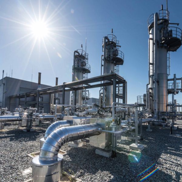 Eine moderne Industrieanlage mit glänzenden Metallrohren und hohen Destillationstürmen unter strahlend blauem Himmel