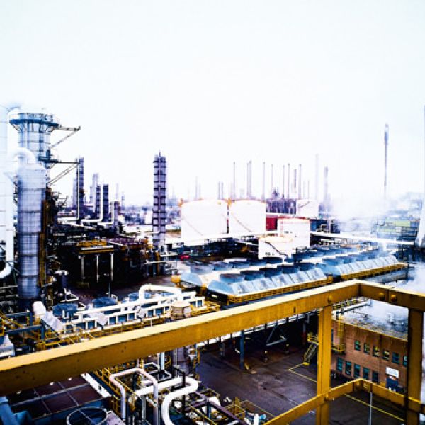 Panorama einer weitläufigen Industrieanlage mit Kühlturm, Schornsteinen und komplexen Rohrleitungssystemen